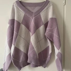 Lila och vit tröja från Dazy - I perfekt skick. Säljer en mysig lila och vit tröja från Dazy med ett rutigt mönster. Tröjan har en v-ringad hals och långa ärmar, perfekt för kyligare dagar. Den är både stilren och bekväm, idealisk för en avslappnad look. Hör av dig vid intresse! 💜