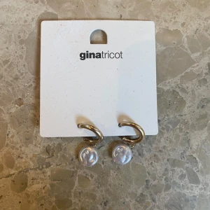Guldörhängen med pärlor från Gina Tricot - Snygga guldörhängen från Gina Tricot med hängande pärlor. Perfekta för att ge en elegant touch till din outfit. Enkla att matcha med olika stilar.