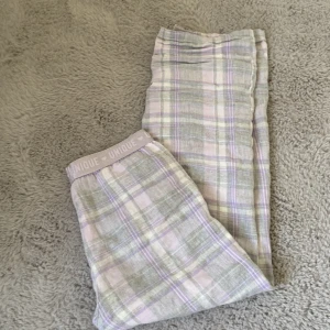 Mysiga rutiga pyjamasbyxor.🫶🏻 - Mysiga byxor med ett rutigt mönster i pastellfärger som lila, grå och vit. De har en elastisk midja med texten 'UNIQUE' och små hjärtan. Perfekta för en avslappnad dag hemma.💗