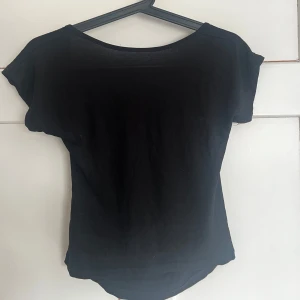 Svart kortärmad topp med öppen rygg - Snygg svart topp med korta ärmar och en stilren öppen rygg. Perfekt för en kväll ute eller en avslappnad dag. Enkel att matcha med olika outfits.