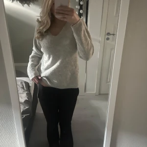 Grå stickad tröja med v-ringning - Säljer en mysig grå stickad tröja med v-ringning. Perfekt för kyligare dagar och passar till många olika outfits. Tröjan har långa ärmar och en bekväm passform.