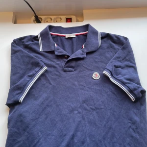 Moncler Piké - Säljer en stilren blå pikétröja från Moncler, säljer eftersom den inte passar mig och har därmed bara legat i garderoben. Den är i mycket bra skick, nfc funkar och det är bara att kontakta vid funderingar!!