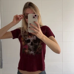 Vinröd t-shirt med dödskallemotiv - Säljer en cool vinröd t-shirt med tryck. Så cool och snygg. Köpt second hand utomlands så vet tyvärr inte var den är ifrån. Skulle säga att det är en storlek xs.