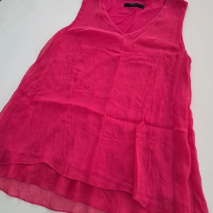 Rosa ärmlös topp från Hallhuber (Siden) - Säljer en snygg rosa ärmlös topp från Hallhuber. Toppen har en v-ringad design och är tillverkad i Siden, perfekt för varma dagar. Den har en längre bakdel för en modern look.