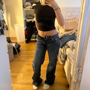Low waist straight jeans - Säljer en svart croppad topp med korta ärmar. Perfekt för en trendig och avslappnad stil. Toppen är tight och framhäver midjan snyggt.