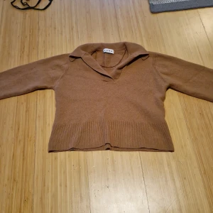 Brun stickad tröja med krage från Wera - Säljer en brun stickad tröja från Wera med v-ringning och bred krage. Tröjan har långa ärmar och ribbade muddar vid ärmslut och nederkant. Tröjan är hyfsat kort, men inte croped. Igentligen storlek M men krympt i tvätten säljer nu är den XS