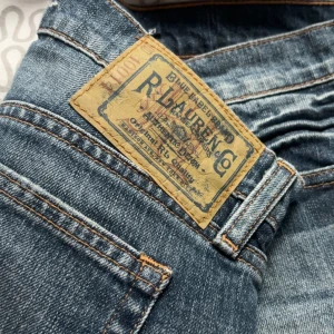 Jeansshorts från Ralph Lauren Sport - OANVÄNDA.Klassiska blå jeansshorts från Ralph Lauren Sport med fem fickor, bälteshällor och knappgylf. Shortsens denim är av bomull och har en snygg, något tvättad look. Perfekta för en avslappnad stil.