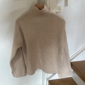 Beige ribbad polotröja från H&M - Säljer en beige ribbad polotröja från H&M i storlek XS. Tröjan har lång ärm och hög krage, perfekt för kyliga dagar. Mjuk och skön med en oversized passform. Passar till allt och är superenkel att styla.