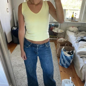Gul ärmlös linnetopp med v-ringning - Säljer en ljusgul ärmlös linnetopp med v-ringad hals. Toppen är croppad och har en enkel, stilren design. Sitter som en storlek S/M. 
