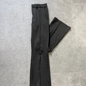 Svarta kostymbyxor med pressveck - Snygga svarta kostymbyxor med bootcut ben och pressveck framtill. Byxorna har hällor för bälte och diskreta sidfickor. Perfekta för en stilren look och passar till många olika outfits. Pris går att diskutera💕