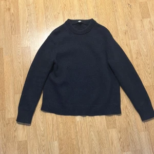 Mörkblå stickad tröja från Arket - Säljer en enkel och stilren mörkblå stickad tröja med rund halsringning från arket. Tröjan har långa ärmar och breda ribbade muddar vid ärmslut och nederkant. Tröjan är storlek L men sitter snarare som M.