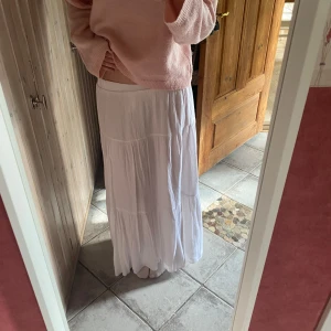 Vit långkjol i luftig bomull - Säljer en vit långkjol i luftig och skön bomull. Kjolen har en flowy passform med flera sömmar som ger ett fint fall. Perfekt för varma dagar och enkel att matcha med olika toppar.