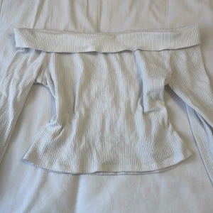 Vit ribbad offshoulder-top från H&M - Säljer en vit ribbad offshoulder-top från H&M. Toppen har långa ärmar och en bred kant upptill som sitter snyggt över axlarna. Storlek 146-152 :)