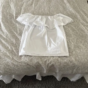 Vit offshoulder topp - Säljer en sååå fin vit offshoulder topp med volangdetalj. Perfekt för en somrig look. Toppen är ärmlös och har en luftig passform. Passar bra till både jeans och kjol. Hör av dig vid intresse! Priset kan diskuteras *💓*Aldrig använd! *priset kan kanske gå ner