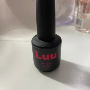 Luu Nail Glue UV/LED - Nagellim från Luu i svart flaska med röd text. Används för att fästa lösnaglar och fungerar med både UV- och LED-lampa. Flaskan har en borste i locket för enkel applicering.endast testad.