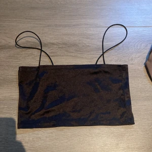 Svart tubtopp med tunna axelband från H&M - Säljer en svart tubtopp från H&M med tunna axelband. Enkel och stilren design, perfekt att matcha med olika outfits. Tillverkad i ett mjukt och stretchigt material.