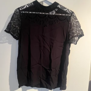 Jättefin svart blus med spetsdetaljer 💕💕 -  en svart blus från Saint Tropez med superfina spetsdetaljer över axlar och ärmar. Blusen har korta ärmar i spets och knapp i nacken