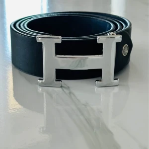 Svart skärpbälte - Säljer ett svart bälte. Bältet är gjort i slätt skinn och Perfekt accessoar för att lyfta din outfit.