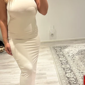 Beige långklänning  - Säljer en stilren beige långklänning från SHEIN. Klänningen är ärmlös med figurnära passform och rund halsringning. 