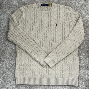 Beige kabelstickad tröja från Polo Ralph Lauren - Säljer denna kabelstickade tröjan som är i mycket bra skick. Storleken är Large men passar något mindre. Hör gärna av dig om du har några frågor eller funderingar kring tröjan!