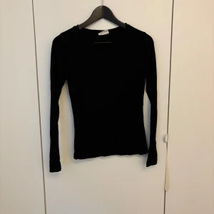 Svart långärmad topp från Gina Tricot - En svart långärmad topp från Gina Tricot, kollektionen Basically Basics. Modellen är tight och har en enkel, klassisk design med rund halsringning. 