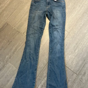 Blå Lowwaist bootcut jeans - Säljer ett par klassiska blå bootcut jeans med normal passform. Jeansen har fem fickor, knapp och dragkedja framtill samt bälteshällor. Perfekta för dig som gillar en tidlös denimlook.