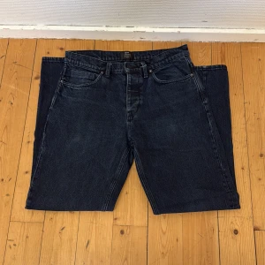 Mörkblå jeans från Neuw - Säljer ett par mörkblå jeans från Neuw med klassisk femficksdesign och silverfärgade knappar. Jeansen har en rak passform och är tillverkade i ett slitstarkt denimtyg. Perfekta för dig som gillar stilrena och tidlösa jeans.