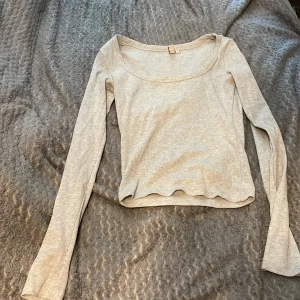 Ljusgrå ribbad långärmad topp från Nelly - Säljer en ljusgrå långärmad topp från Nelly. Toppen är ribbad med rundad halsringning och har en lätt vågig nederkant. Perfekt att styla till jeans eller kjol.