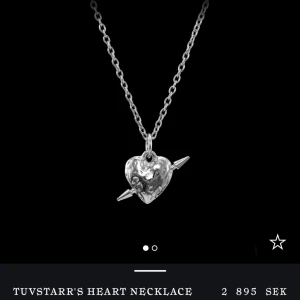 Tuvstarr's Heart halsband i silver - Unikt halsband från Maria Nilsdotter i modellan Tuvstarr’s heart necklace modellen med ett coolt hjärthänge i silverfärg och en pil som går rakt igenom. Kedjan är tunn och stilren. Äkta silver (925). De är använt men har inga defekter eller nåt som tyder på det. Boxen medkommer❣️