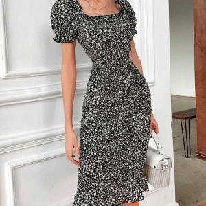 Svart blommig långklänning med puffärm - Supersnygg svart långklänning med små vita blommor, puffärmar och smockad midja. Klänningen har fyrkantig ringning, volangkant nertill och sitter figurnära. Helt oanvänd! Fungerar som xs/s 🤍