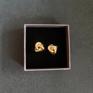 Guldiga knutformade örhängen - Snygga örhängen i guldton med knutdesign. De är små, eleganta och passar perfekt om du gillar stilrena accessoarer och är enkla att matcha med andra smycken.💕💕💕😊😊