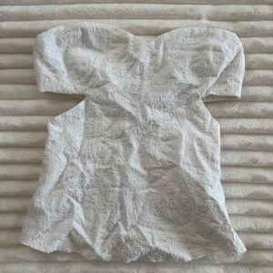 Vit spetsig axelbandslös tubtopp - Superfin vit axelbandslös korsett/tubtopp med spets och bandeau-form. Toppen är från Zara och aldrig använd. 