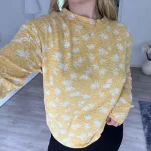 Gul tröja från Carin Wester - Superfin gul långärmad tröja från Carin Wester med vitt blommigt mönster. Tröjan har en avslappnad passform och rund halsringning. Perfekt för dig som gillar färg och mönster i garderoben. Önskar du veta exakta mått? Tveka inte att höra av dig!