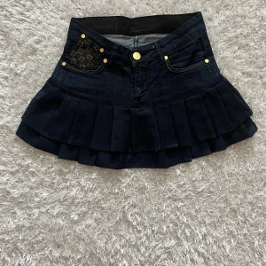 Mörkblå  jeanskjol  - Lågmidjad jeanskjol omsydd från ett par jeans. Midjemått tvärsöver - ca 33  Längd - 31cm