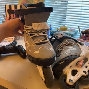 Gråa inlines från Oxelo - Säljer ett par gråa inlines från Oxelo med vita och svarta detaljer. Skorna har snörning, kardborreband och spänne för extra stabilitet. Yttermaterialet är syntet och mesh, och hjulramen är i vit plast. Max hjulstorlek är 76 mm. Storlek är 36 eller 35 och uppåt 