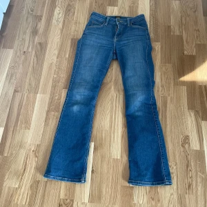 Lee Breese Bootcut jeans blå W26 L31 - Snygga blå bootcut jeans från Lee, modell Breese Boot. Klassisk femficksdesign, normalhög midja och dragkedja. Jeansen har en lätt utsvängd passform nertill och är gjorda i mjukt denimtyg med lite stretch för extra komfort.