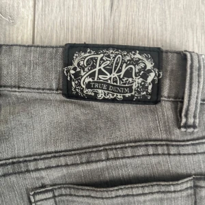 Grå skinny jeans från Isfn True Denim - Snygga grå jeans från Isfn True Denim med klassisk femficksdesign och broderade bakfickor. Jeansen har en smal passform och raka ben, perfekt för en stilren och modern look. Tillverkade i mjukt jeanstyg som sitter skönt hela dagen.