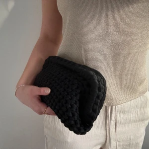 Svart handvirkad clutch - Säljer en svart handvirkad clutch / handväska som jag har virkat! Väskan är i ett mjukt garn och är väldigt rymlig! Kan bäras i handen som en clutch eller bäras i handtaget.