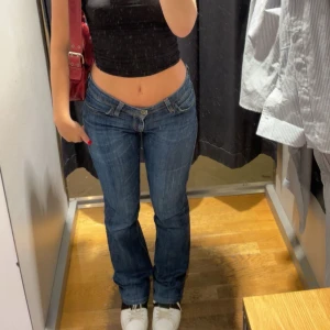 Levi's 572 Bootcut Jeans Blå - Snygga blå Levi's 572 bootcut jeans med klassisk femficksdesign och kontrastsömmar. Jeansen har låg midja och är tillverkade i slitstarkt denim med dragkedja och knapp framtill. Perfekta för dig som gillar en avslappnad och tidlös look.