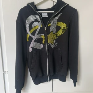Rhinestone zip hoodie - Zip hoodien är från AimfortheMoon och är i storlek XS. Hoodien har tappat ganska mycket rhinestones på vänstra sidan, men är ändå väldigt bekväm samt unik. Skriv för mer frågor!