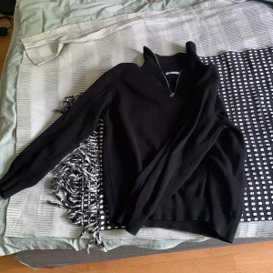 Svart stickad half zip-tröja från Zara - Svart stickad tröja från Zara med hög krage och half zip-dragkedja. Tröjan har lång ärm och ribbade muddar vid ärmslut och nederkant. Perfekt för lager-på-lager och chill höst- eller vinterstil.