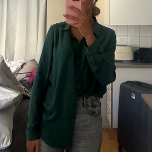 Mörkgrön skjorta från Vila - Säljer en stilren mörkgrön skjorta från Vila i storlek S. Skjortan har klassisk krage, knäppning framtill och långa ärmar. 