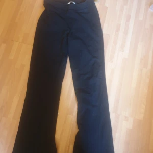 Svarta bootcut byxor stl 164 - Svarta byxor med bootcut-modell från märket Cubus. Byxorna har en klassisk, enkel design med utsvängda ben och normal passform. Perfekta för dig som gillar en stilren look och vill ha ett par bekväma byxor till vardags.