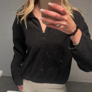 Svart fleece half zip från Weekday - Svart fleece-tröja från Weekday i storlek S. Tröjan har en halv dragkedja framtill, långärmad modell och är gjord i mjukt, mysigt fleecematerial. Perfekt för lager-på-lager och chill dagar. Enkel och stilren design som funkar till det mesta.