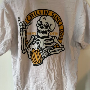 Vit Vans t-shirt med skelettprint - Vit t-shirt från Vans i bomull med stort tryck på ryggen. Använd men fortfarande bra kvallite. Har en lite missfärgning på halsen.