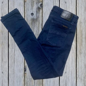 Mörkblå jeans från Nudie Jeans - Snygga mörkblå jeans från Nudie Jeans. Jeansen är tillverkade i ekologisk bomull och har en slim fit passform med raka ben. Perfekta för dig som gillar stilrena och tidlösa jeans med diskreta detaljer. Jeansen är i mycket bra skick och tillverkade av ekologisk bomull. Tveka inte att höra av vid funderingar😇