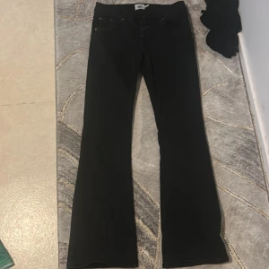 Svarta bootcut jeans från 157 - Svarta jeans från 157 med klassisk femficksdesign och bootcut-ben. Jeansen har normal passform och är tillverkade i ett mjukt bomullsmaterial med lite stretch. Perfekta för dig som gillar en tidlös look med lite utsvängda ben.