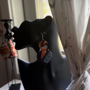 Färgglada statementörhängen från Shop with Tyra - Unika statementörhängen i flera lager med geometrisk form. Färgerna är orange, svart, vit och blå med inslag av glittrigt material. Perfekta för dig som vill sticka ut och addera färg till din look. Följ oss för mer på Instagram; @shop_with_tyra