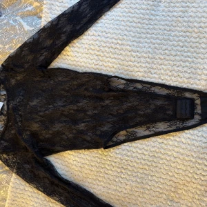 Svart spetsklänning med lång ärm - Säljer en svart, genomskinlig spetsbody med lång ärm. 