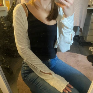 Vit ribbad kofta med rosetter - Superfin vit ribbad kofta med långa ärmar och söta rosettdetaljer längs ärmarna.